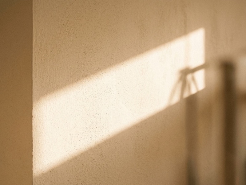 Diagonal band of sunlight falling across a plain plaster wall