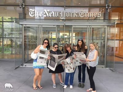 A cityHUNT team reading copies of The New York Times outside the newspaper's building