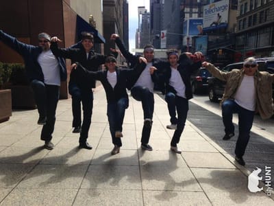 A cityHUNT team of six doing a kick line on a New York City sidewalk