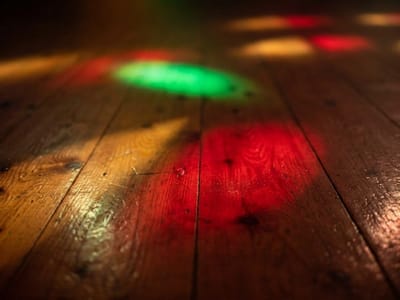 Red and green spotlights shining on a worn wooden dance floor