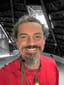 Benjamin Peace Hoffman smiling in a red shirt under a thatched roof