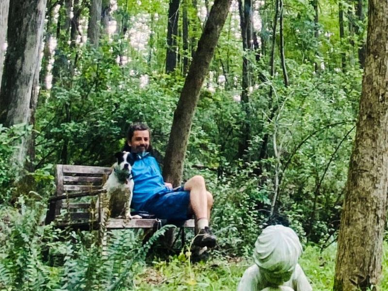 Ben Hoffman sitting on a wooden bench in the woods with his dog Otto