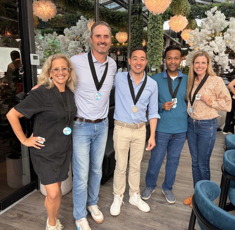 Ben Hoffman posing with four participants wearing medals at a cityHUNT scavenger hunt event