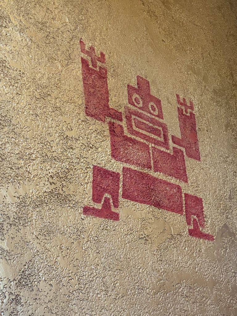 Red geometric figure in pre-Columbian style painted on a textured plaster wall