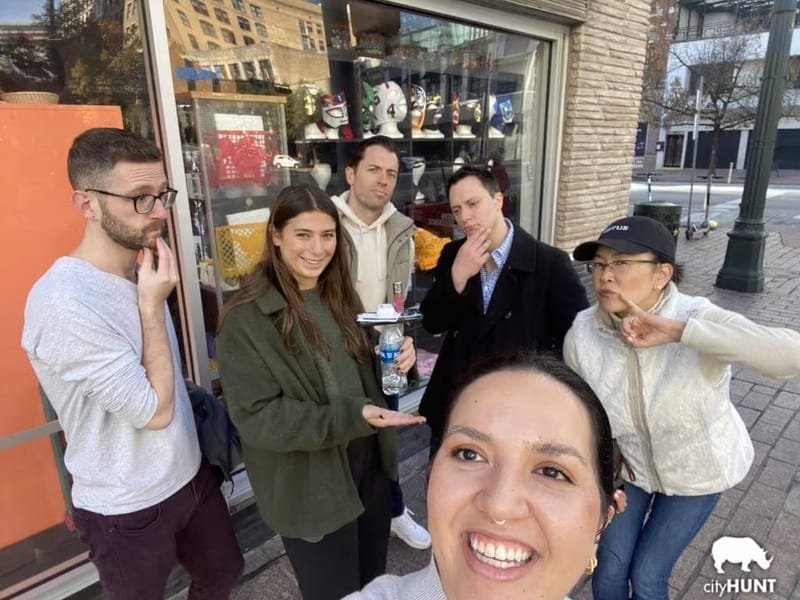 A cityHUNT team posing for a selfie outside a shop window on a city street