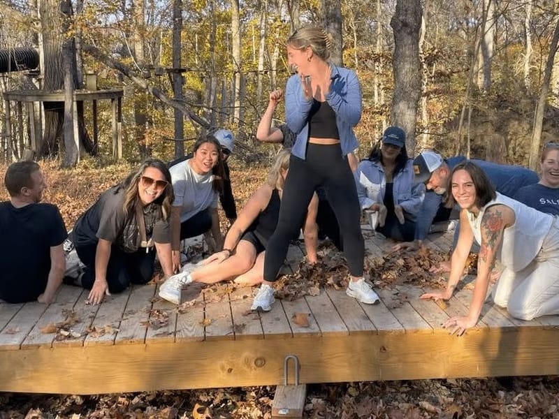 A cityHUNT team laughing together on a wooden platform in the autumn woods