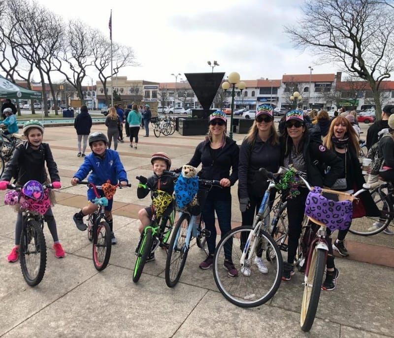 A group of adults and children standing with their bicycles in a town square