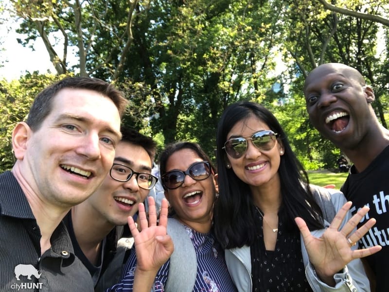 Five teammates taking a selfie together among the trees in a park