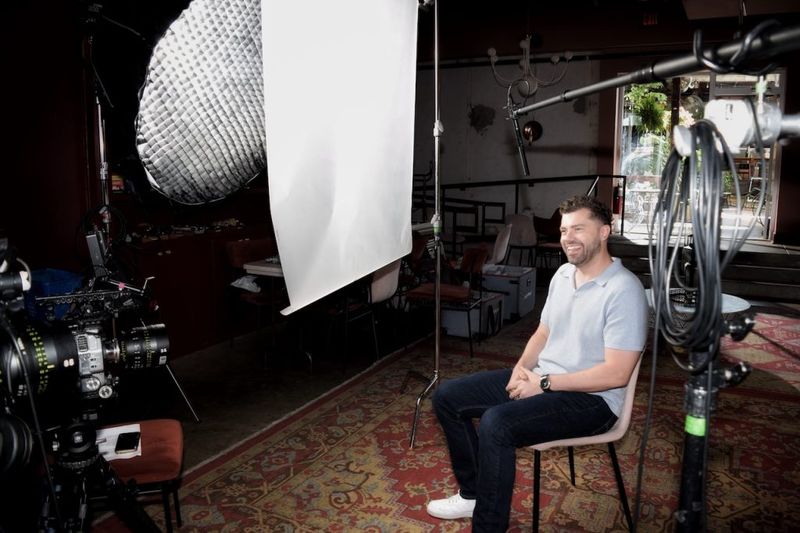 Ben Hoffman seated and smiling during a professional video interview shoot in Nashville, surrounded by studio lighting and a cinema camera